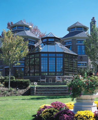 The exterior of a glass conservatory overlooking the back garden of an estate.